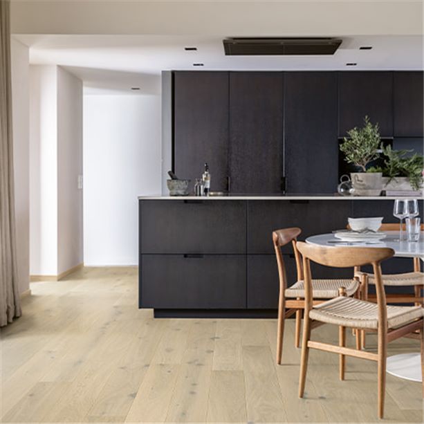 black kitchen with dining table and a beige wooden floor